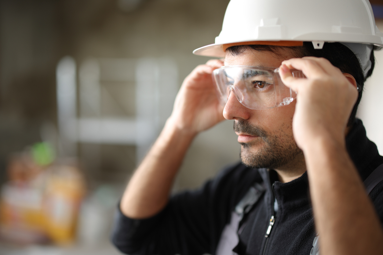 Construction worker adjusting safety glasses while wearing a hard hat